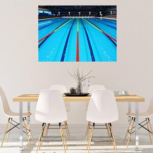 Puede incluir: Una piscina azul con varios carriles marcados por líneas rojas, blancas y negras. La piscina está vacía y el agua está clara.