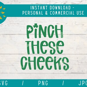May include: Green text on a white wood background reads "Pinch These Cheeks".  The text is decorated with shamrocks.
