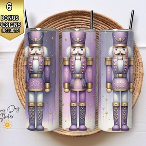 May include: Three stainless steel tumblers with a nutcracker design in shades of purple, gold, and white. Each tumbler features a black straw and is set against a woven basket. The image includes text that says "6 Bonus Designs Included!"