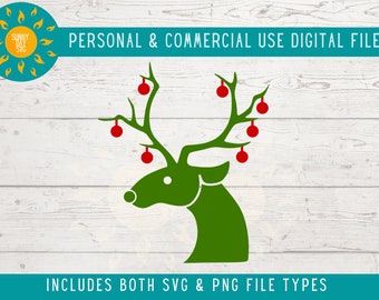 May include: A green reindeer head silhouette with red ornaments on its antlers. The background is a white woodgrain pattern. The text "PERSONAL & COMMERCIAL USE DIGITAL FILES" is at the top of the image and the text "INCLUDES BOTH SVG & PNG FILE TYPES" is at the bottom of the image.