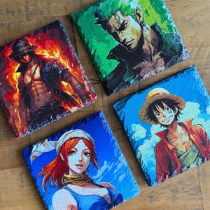 May include: Four square slate coasters featuring colorful anime character art. The coasters depict characters in vibrant detail, with a fiery background, a green-toned portrait, and two characters against blue skies.