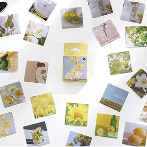 May include: A set of 32 yellow and white floral themed stickers in a small box. The stickers feature images of flowers, lemons, and other nature-inspired designs.