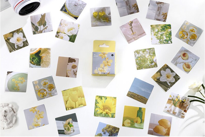 May include: A set of 32 yellow and white floral themed stickers in a small box. The stickers feature images of flowers, lemons, and other nature-inspired designs.