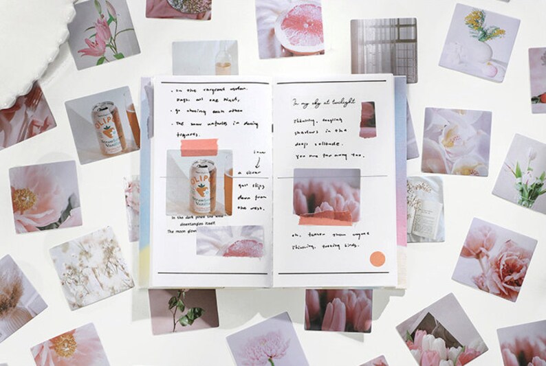 May include: A collection of square stickers featuring various images, including flowers, fruit, and a can of soda. The stickers are arranged around an open notebook with handwritten text and a few more stickers on the pages. The notebook has a rainbow gradient on the cover.