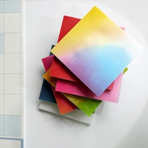 May include: A stack of colourful square sticky notes with a gradient of blue, purple, yellow, and red. The notes are arranged in a stack with the blue and purple gradient on top.