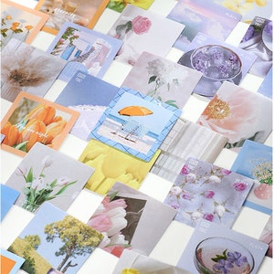 May include: A collection of square cards with various images, including flowers, landscapes, and abstract designs. The cards have a white background and feature the text "PLAY" and "TBC" on some of them.