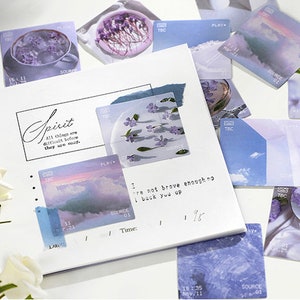 May include: A collection of decorative stickers featuring pastel blue and purple colors with floral and landscape designs. The stickers have text that reads "Spirit", "Play", "Source", "TBC", and "All things are difficult before they are easy".