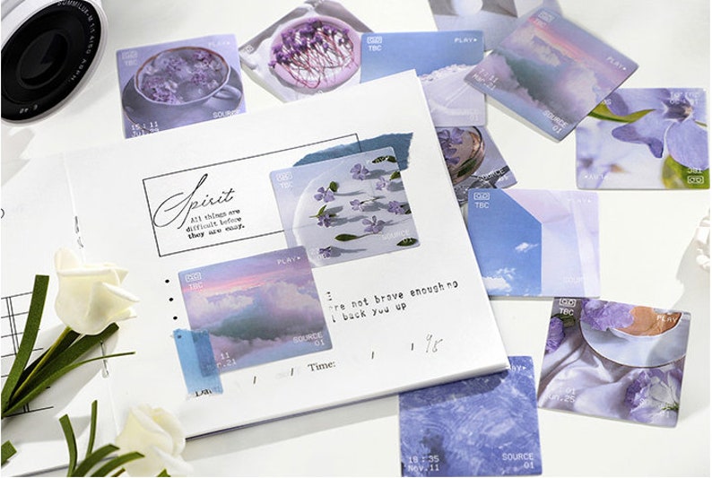 May include: A collection of decorative stickers featuring pastel blue and purple colors with floral and landscape designs. The stickers have text that reads "Spirit", "Play", "Source", "TBC", and "All things are difficult before they are easy".