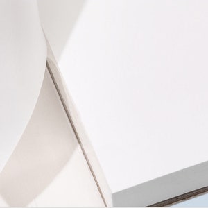 May include: A close-up of a white surface with a subtle shadow. The surface appears to be smooth and reflective.