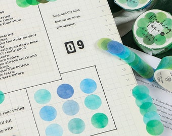 May include: A sheet of paper with a grid pattern and a variety of colourful round stickers. The stickers are in shades of blue, green, and teal. The paper also has text that says "Sing, and the hills borrow its mirth, will answer;" and "09".