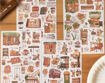 Puede incluir: Un conjunto de 3 hojas de pegatinas de estilo vintage con ilustraciones de tiendas, cafés y otros edificios. Las pegatinas están impresas en papel texturizado y tienen un aspecto de acuarela. Las pegatinas están numeradas del 1 al 9.
