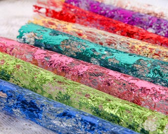 May include: A selection of rolled decorative mesh in various colours, including blue, green, pink, teal, red, yellow, and purple. The mesh has a metallic sheen and an open weave, ideal for crafts and gift wrapping, presented in rolls.