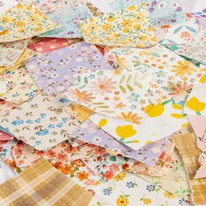 May include: A collection of fabric scraps featuring a variety of floral patterns in shades of pink, yellow, blue, and green. The fabric scraps are arranged in a random pattern and are ideal for crafting projects.