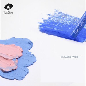 May include: A close-up of oil pastels on oil pastel paper. The paper is white and the pastels are blue and pink. The text "OIL PASTEL PAPER" is printed on the paper. The brand name "Paul Rubens" is printed on the blue pastel.