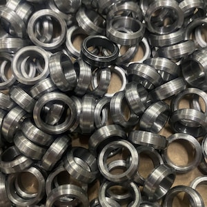 May include: A pile of silver metal rings, each with a slightly different size and shape. The rings are all made of a smooth, shiny metal and have a slightly rounded edge.