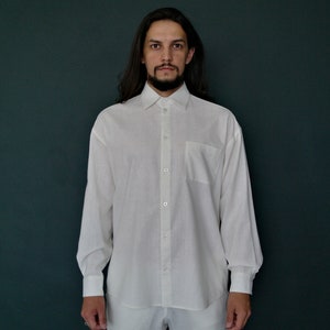 May include: A white long-sleeved button-down shirt with a pocket on the left chest.