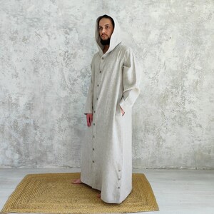 Men's Undyed Hooded Linen Kaftan with Button Front Side Slits and Deep Pockets, side view showing an undyed, hooded linen kaftan showing the relaxed fit and side pockets.