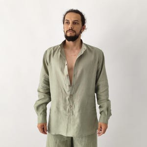 May include: A light green linen shirt with a mandarin collar and long sleeves. The shirt has a button-down front and is paired with matching pants. The fabric appears to be lightweight and breathable, suitable for warm weather.