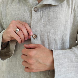 Men's Undyed Hooded Linen Kaftan with Button Front Side Slits and Deep Pockets, close-up showing the button detail and fabric texture of the undyed linen kaftan.