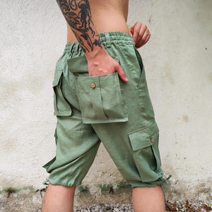 May include: Green cargo shorts with multiple pockets and a drawstring waist.