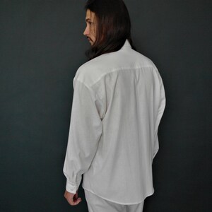 May include: A white long-sleeved button-down shirt with a relaxed fit.