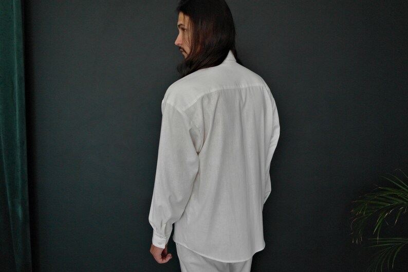 May include: A white long-sleeved button-down shirt with a relaxed fit.