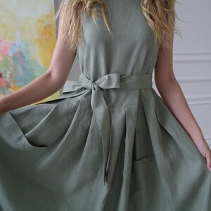 Women's pleated maxi linen dress close-up showing waist tie and patch pockets