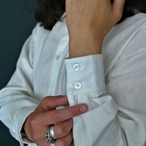 May include: A white long-sleeved shirt with a button-up closure and double button cuffs.