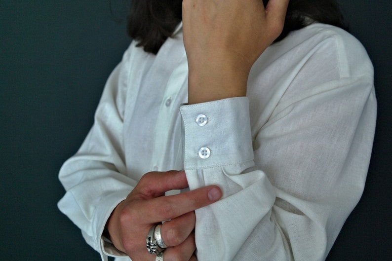 May include: A white long-sleeved shirt with a button-up closure and double button cuffs.