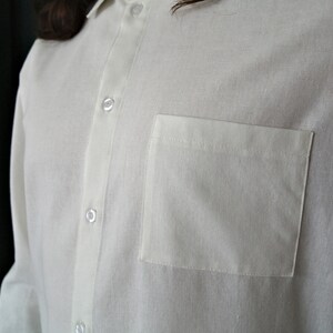 May include: A white long-sleeved button-down shirt with a single chest pocket.