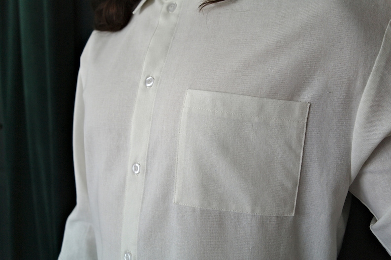 May include: A white long-sleeved button-down shirt with a single chest pocket.