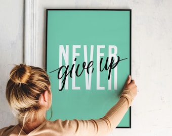 May include: A framed poster with a teal background and the words "NEVER GIVE UP" in white and black script. The poster is being held by a person with blonde hair.