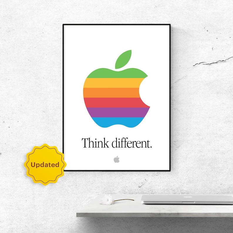 May include: A black framed poster with a rainbow colored Apple logo and the text "Think different." The poster is hanging on a white wall.
