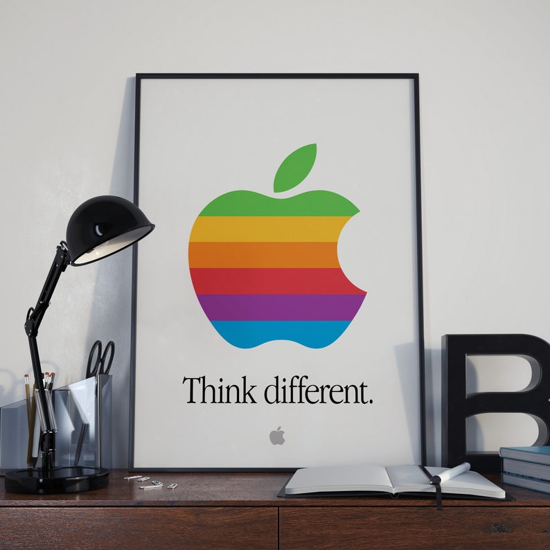 May include: A black framed poster with a rainbow colored Apple logo and the text "Think different." The logo is a stylized apple with a bite taken out of the right side.