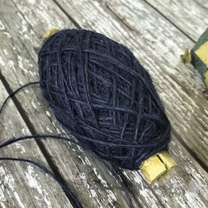 May include: A ball of dark blue twine with a yellow paper label. The twine is wound around a cardboard spool.