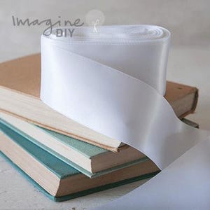 Wit satijnen lint in verschillende breedtes: 13 mm, 16 mm, 19 mm, 25 mm, 38 mm of 100 mm breed satijnen lint