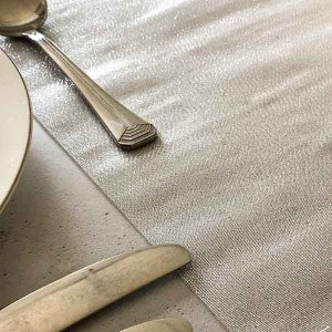 May include: A silver table runner with a subtle shimmer. The runner is made of a soft, silky fabric and is perfect for adding a touch of elegance to any table setting.