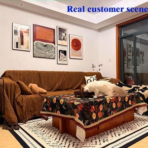 May include: A living room scene with a brown sofa, a floral patterned coffee table, and a white cat. Artwork hangs on the wall above the sofa. A rug with a geometric pattern is on the floor. The text "Real customer scene" is at the top.