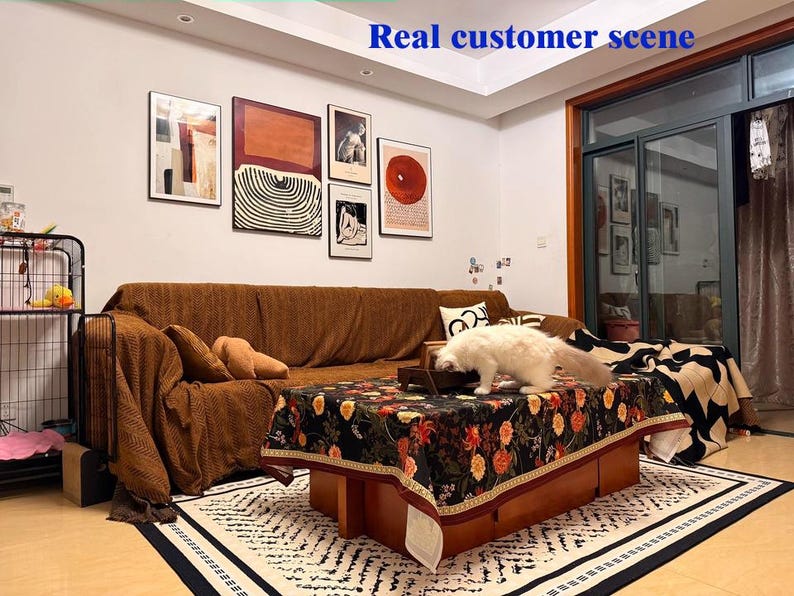May include: A living room scene with a brown sofa, a floral patterned coffee table, and a white cat. Artwork hangs on the wall above the sofa. A rug with a geometric pattern is on the floor. The text "Real customer scene" is at the top.