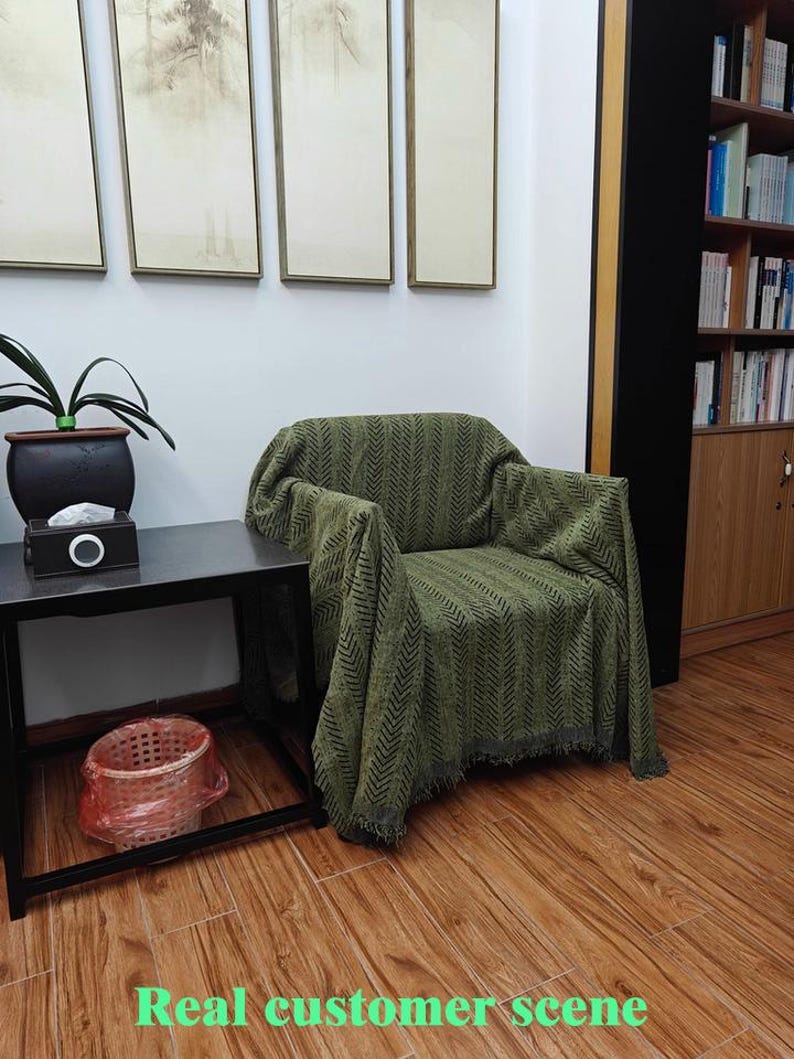 May include: A green patterned throw blanket draped over an armchair. The blanket has a chevron design and fringe along the bottom. The words "Real customer scene" are at the bottom of the image.