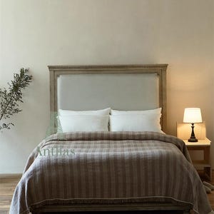 Pu&ograve; includere: Un letto con testiera in legno chiaro e una coperta a righe marroni. Il letto &egrave; fatto con cuscini bianchi e un copriletto abbinato. Una piccola lampada &egrave; su un comodino accanto al letto. La parola "Antillas" &egrave; visibile.