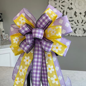 Peut inclure: Un nœud violet et jaune avec un motif vichy et un imprimé de marguerite. Le nœud est noué autour d'une lanterne noire.