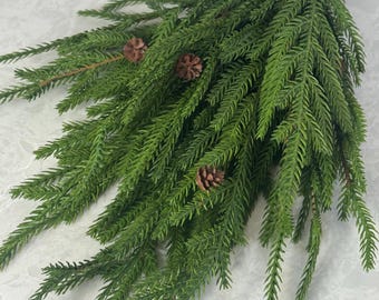 May include: An artificial sprig of green foliage with small brown pine cones. The stem is brown. This decorative piece is suitable for seasonal home decor and craft projects. The sprig is ideal for adding a touch of nature.