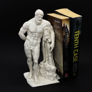 Puede incluir: Un separador de libros impreso en 3D blanco con una escultura de un dios griego de pie junto a un tronco de árbol. El separador de libros sostiene dos libros, uno titulado "The Tenth Case" y el otro titulado "Richard Matheson As I See Legends".