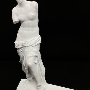 May include: White 3D printed statue of the Venus de Milo, a famous Greek sculpture. The statue is standing on a white base.