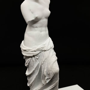 May include: White 3D printed statue of a woman standing on a white base. The statue is a replica of the Venus de Milo, a famous Greek sculpture.