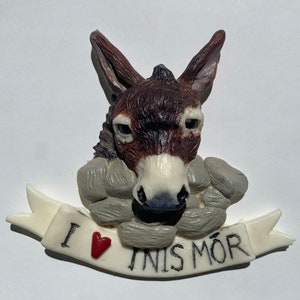 May include: A brown donkey figurine with a white nose and a red heart on a white banner that says "I  INIS MÓR".