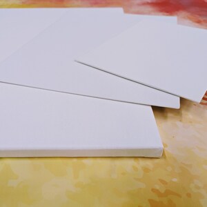 May include: Three white canvas boards of different sizes stacked on top of each other. The boards are blank and ready for painting.