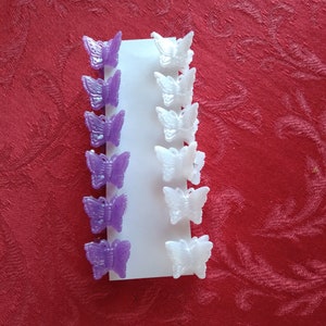 May include: A set of 10 butterfly hair clips, 5 purple and 5 white. The clips are arranged in two rows on a white background.