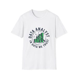 May include: White t-shirt featuring a circular graphic with the words "DATA ANALYST" and "IN DATA WE TRUST." The graphic includes a bar graph and a magnifying glass in green and black. The t-shirt is a short-sleeved crew neck.